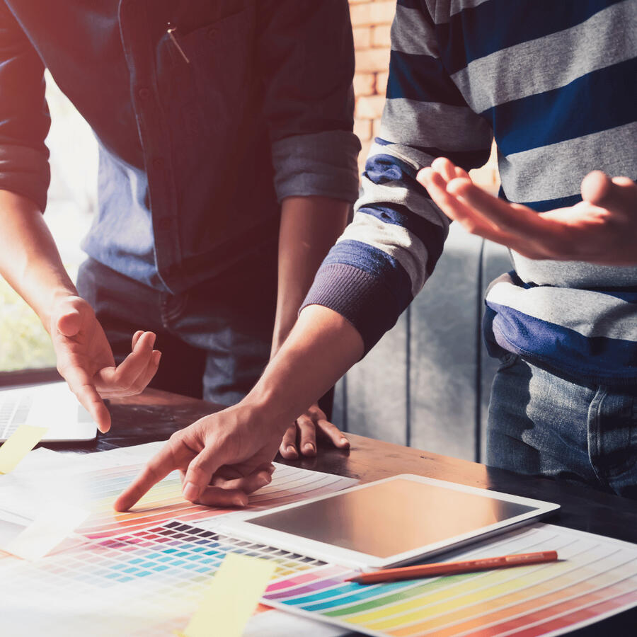 Image of two people leaning over a desk collaborating on a shared project.